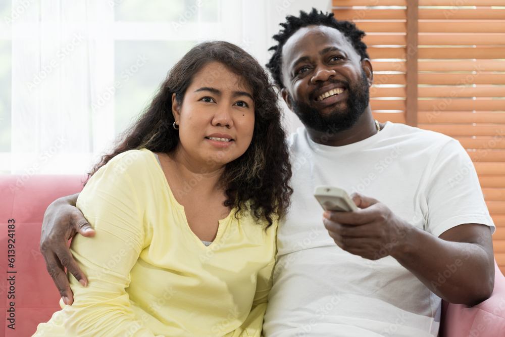 Happy young Asian woman and African American male spending time together at home Happy young Asian woman and African American male spending time together at home