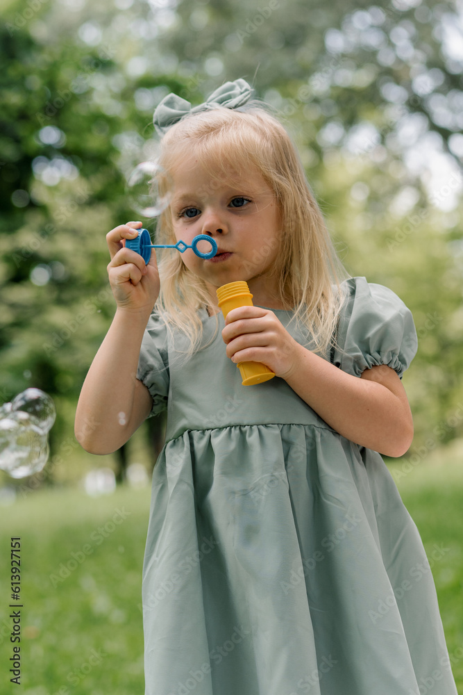 portrait Cute little girl blowing soap bubbles having fun in the park on a summer day Child playing Happy Children's Day Fun and carefree childhood