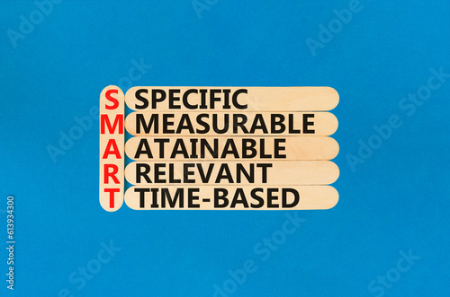 SMART symbol. Concept words SMART specific measurable attainable relevant time-based on stick. Beautiful blue background. Business SMART specific measurable attainable relevant time-based concept.