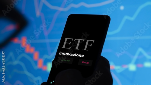 An investor analyzing an etf fund on a phone. Italian text: Innovation, buy, sell.