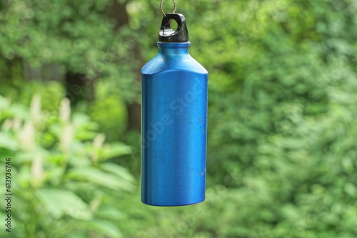 one modern aluminum closed empty blue new flask for various drinks on the background of nature