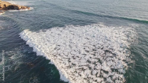 Drone tracking shot from aerial following surfers on Pacific Ocean waves surfing near sunset cliffs on southern California beach water surface photo