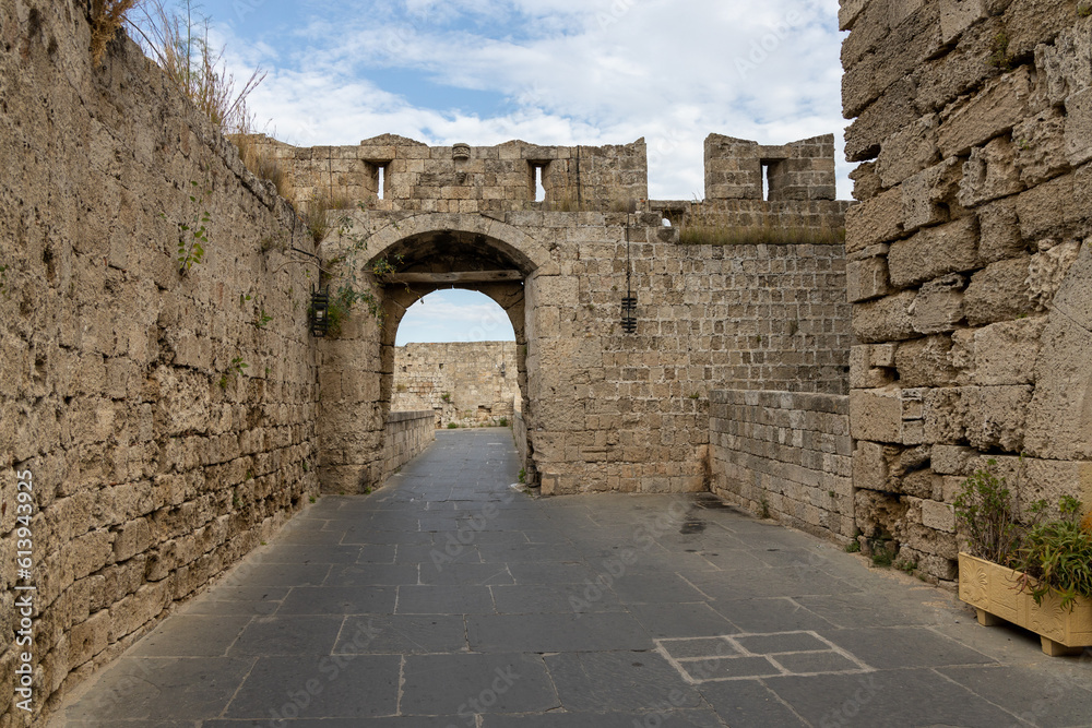 Empty street in old town in Rhodes, Greece surrounded by fortification stone walls