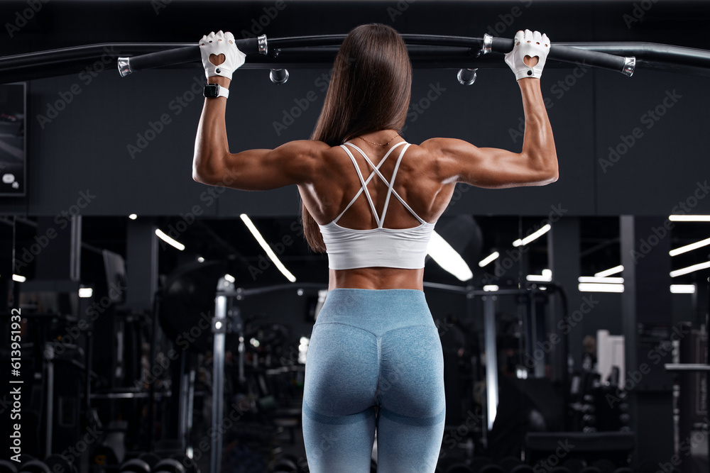 Fitness woman doing pull-ups exercise for back muscles, working out in gym  . Athletic girl training Stock Photo