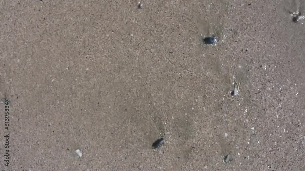 A heart drawn on the sand is being washed out by the waves on a sunny  summer day by the sea.
A concept of separation, loss, solitude and change. 
