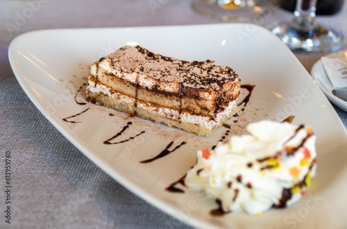 Tiramisu cake with cream, on white plate. 