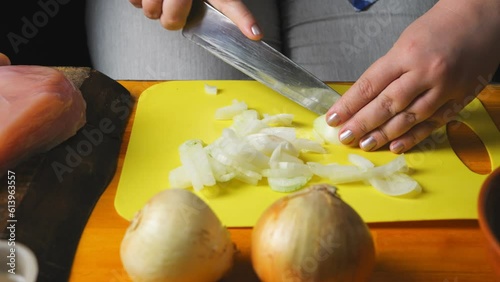 Women's hands cut onion for cholent with a large knife on a plastic board. close-up photo