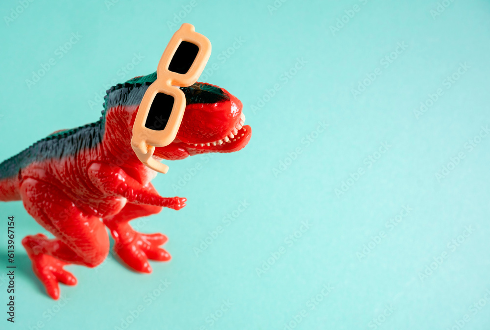Fototapeta premium Coo red dinosaur wearing orange sunglasses on blue background. Copy space. Minimal art.
