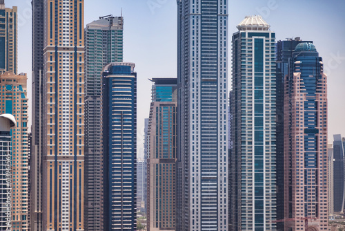 Close-up of Dubai front modern skyscrapers sunshine summer day  full frame urban backdrop. Cityscape UAE house new towers. Construction and modern architecture concept. Copy ad text space  wallpaper