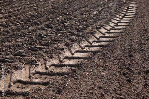 Close-up of a tractor wheel print in dark soft ground.