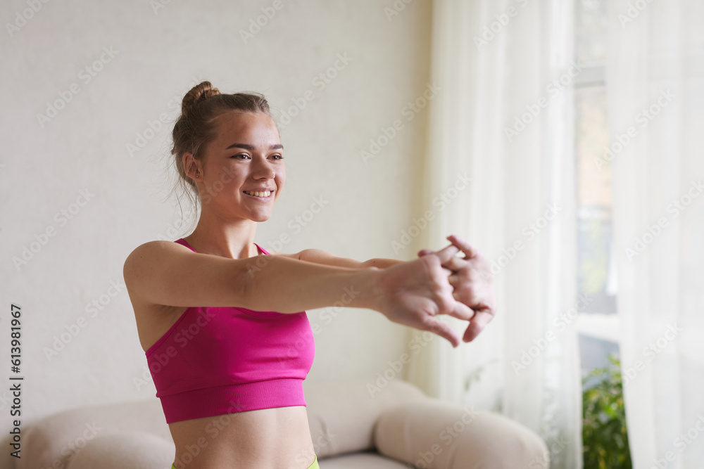 a girl in bright sportswear does exercises for her hands, the concept of doing sports at home
