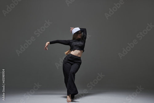 a girl in dark clothes dances and jumps on a dark background background modern dance