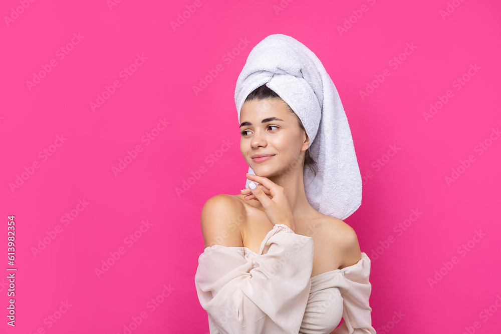 Portrait of young beautiful woman after bath. Beauty face of a cheerful attractive girl with towel on head against a pink background. Portrait of young beautiful woman after bath. Beauty face of a cheerful attractive girl with towel on head against a pink background.