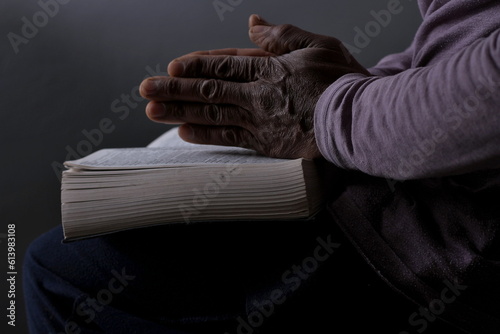 man praying with bible with black background with people stock photo