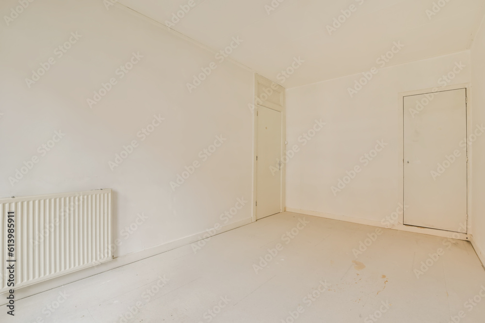 an empty room with white walls and flooring, there is a rad door on the right hand side an empty room with white walls and flooring, there is a rad door on the right hand side