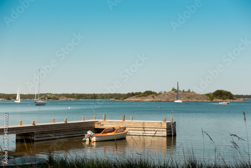 Slika na platnu Stockholm archipelago in sunset with small boat moored to pier with sailing boat