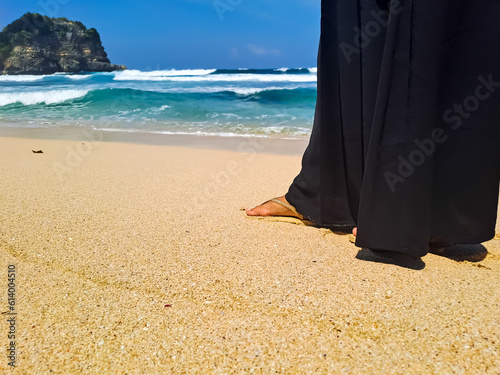 Female leg with sandal and long skirt stepping on white sand in the beach. Summer vacation concept