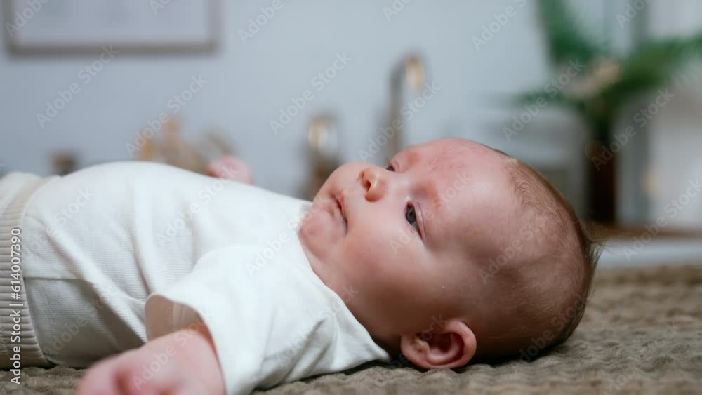 Cute baby boy lies on his back. Newborn wearing white tshirt waves