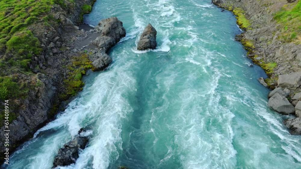Large river flows through a rocky landscape in Iceland. Clear turquoise glacial water. Beautiful summer nature.