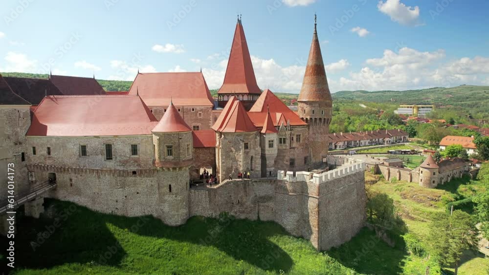 Aerial drone view of the Corvin Castle located in Hunedoara, Romania. People inside. Greenery and buildings around