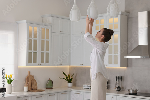 Woman changing lightbulb in ceiling lamp at home