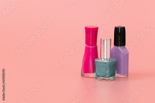 Pink, purple and teal nail polish bottles on pink background. Copy space. © Alyh M