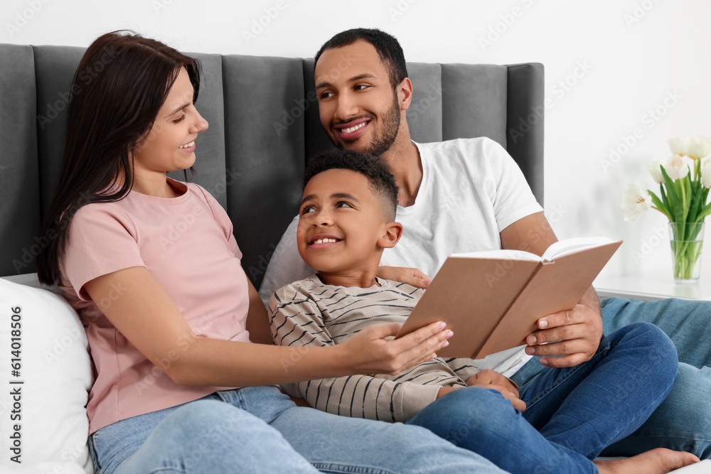 Happy international family reading book on bed Happy international family reading book on bed
