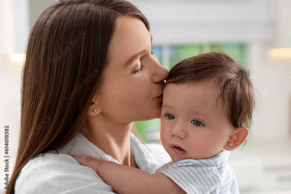 Happy mother kissing her little baby indoors, closeup Happy mother kissing her little baby indoors, closeup
