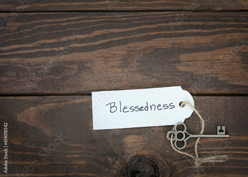 The key of blessedness concept isolate. Silver key with a label on wood table.