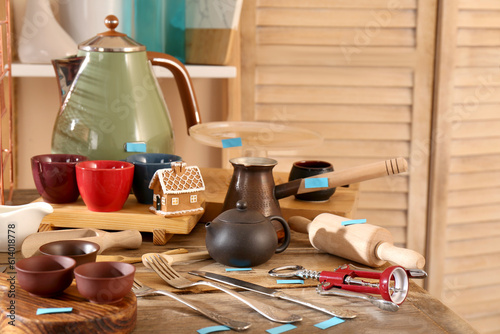 Many different cooking utensils on wooden table indoors. Garage sale