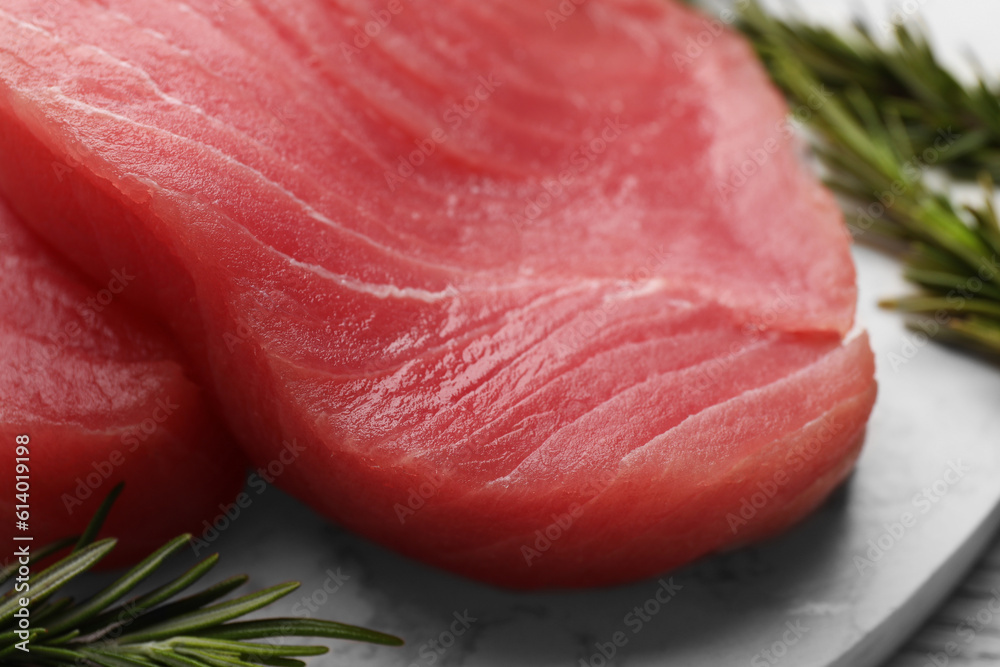 Fresh raw tuna fillets with rosemary on table, closeup Fresh raw tuna fillets with rosemary on table, closeup