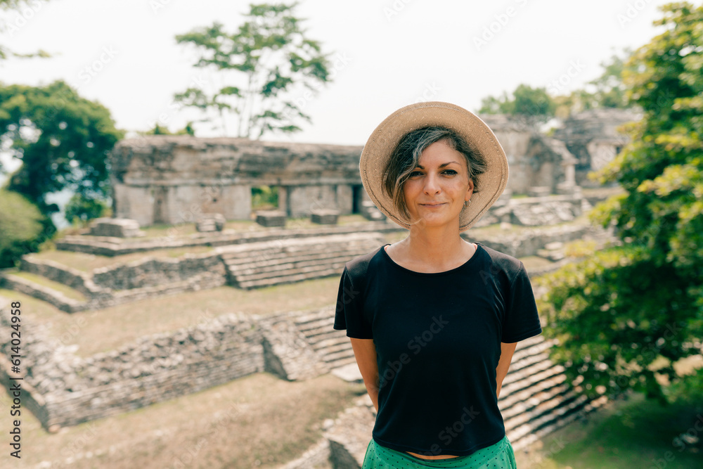 Obraz premium Hiker wonam with a hat looking at ancient Mayan ruins