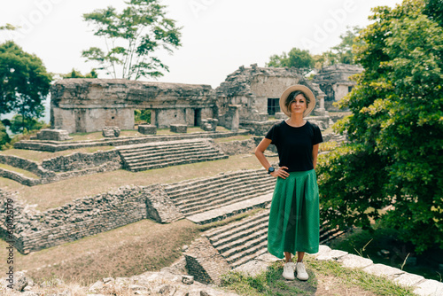 Hiker wonam with a hat looking at ancient Mayan ruins photo