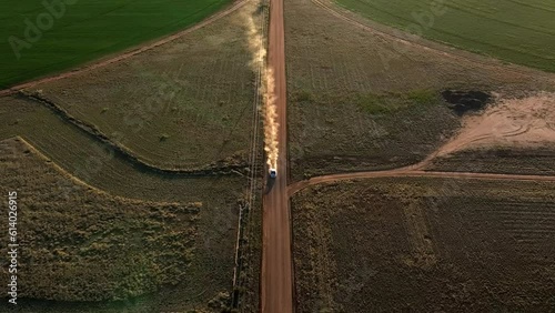 Aerial shot of car driving on dirt road in near pivots with green farm growth in Willcox, Arizona, wide downward angle drone shot photo