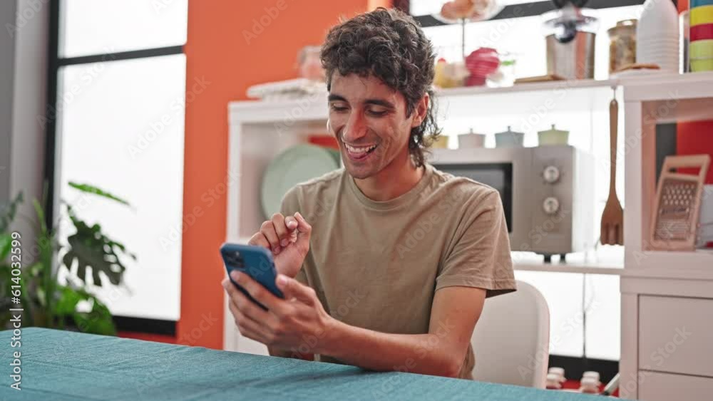 Young hispanic man using smartphone sitting on table at dinning room Young hispanic man using smartphone sitting on table at dinning room