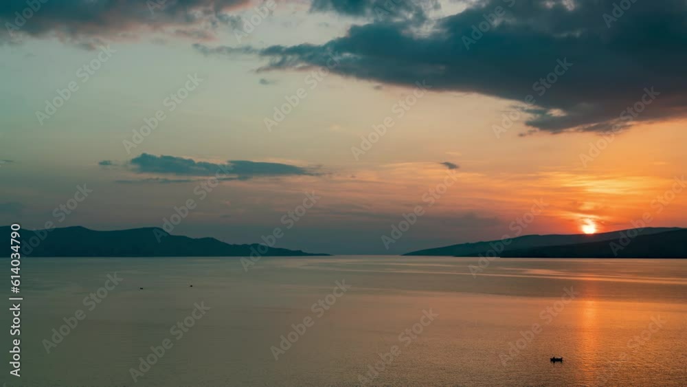 Aerial timelapse of Senj coast in Croatia during autumn. The scene captures a colorful sea sunset, silhouettes of mountains, and scattered clouds creating a calm yet stunning view. Aerial timelapse of Senj coast in Croatia during autumn. The scene captures a colorful sea sunset, silhouettes of mountains, and scattered clouds creating a calm yet stunning view.