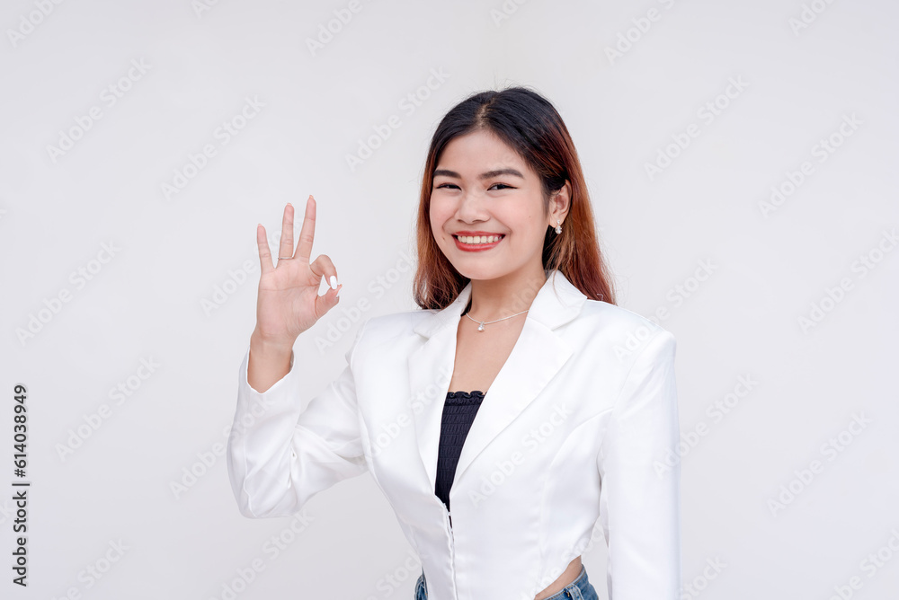 A happy and contented young woman making okay gesture with her hand. Isolated on a white background. A happy and contented young woman making okay gesture with her hand. Isolated on a white background.