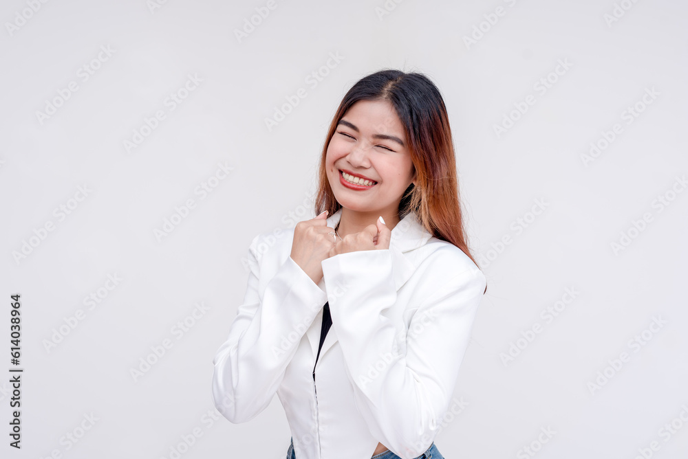 An ecstatic young woman with raised fists and closed eyes in a yes gesture. Isolated on a white background. An ecstatic young woman with raised fists and closed eyes in a yes gesture. Isolated on a white background.