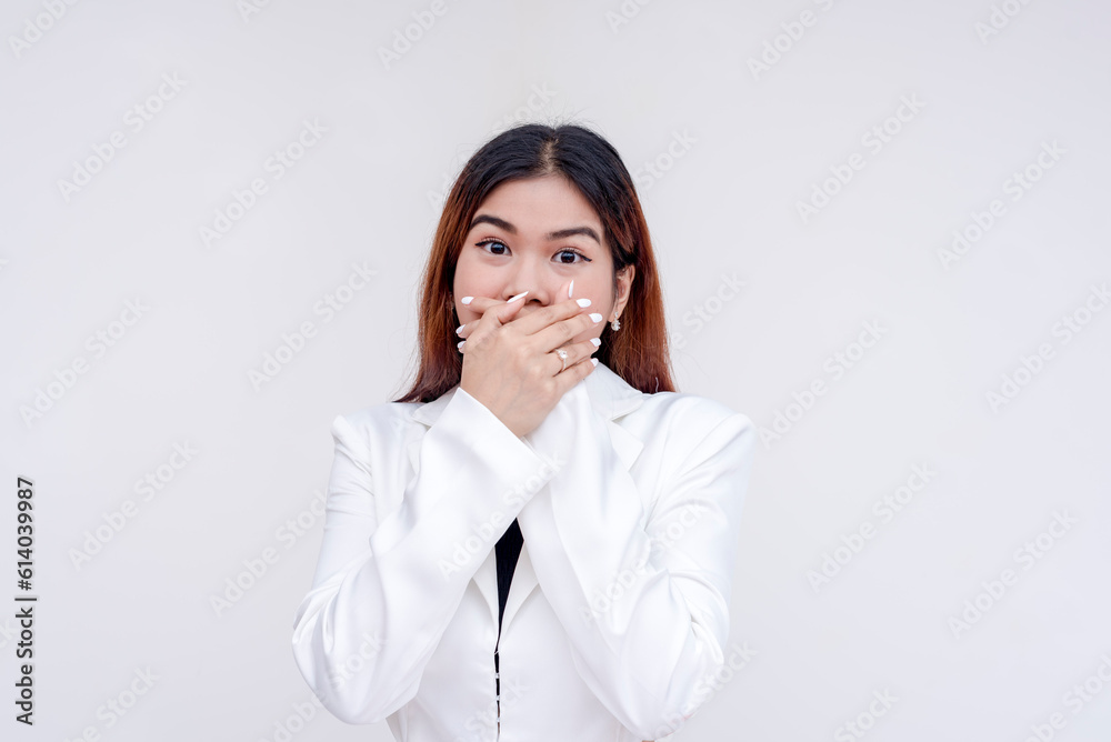 A surprised young woman with eyebrows raised covering her mouth with both hands in shock. Isolated on a white background. A surprised young woman with eyebrows raised covering her mouth with both hands in shock. Isolated on a white background.