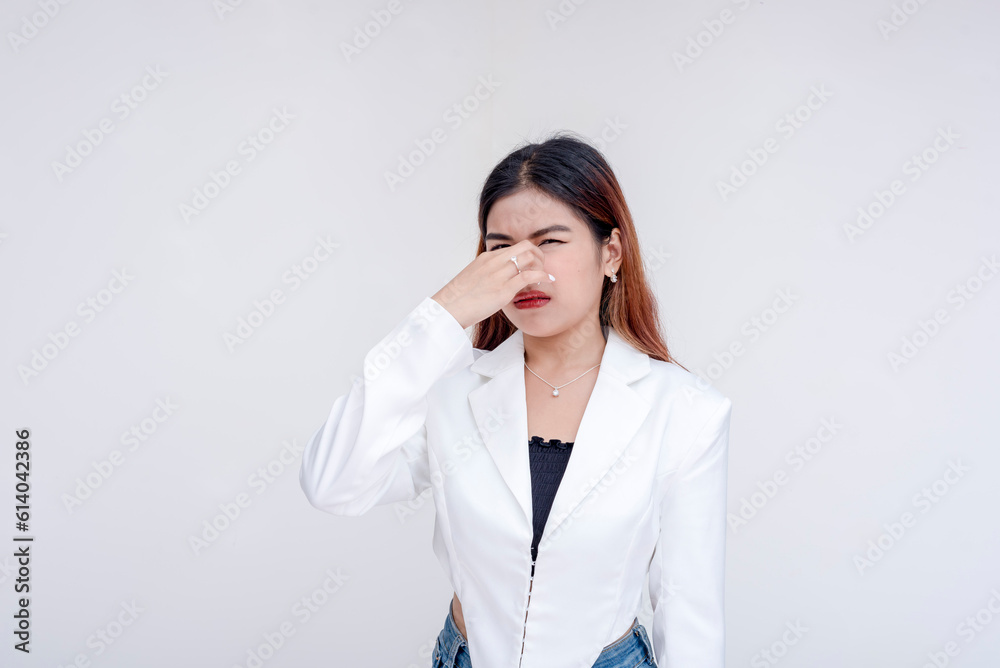 A distressed and irritated young woman pinching her nose to avoid a stinky smell. Isolated on a white background. A distressed and irritated young woman pinching her nose to avoid a stinky smell. Isolated on a white background.