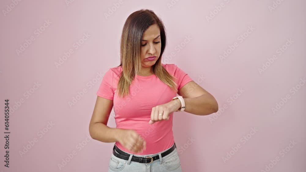Middle eastern woman stressed looking at the watch over isolated pink background Middle eastern woman stressed looking at the watch over isolated pink background