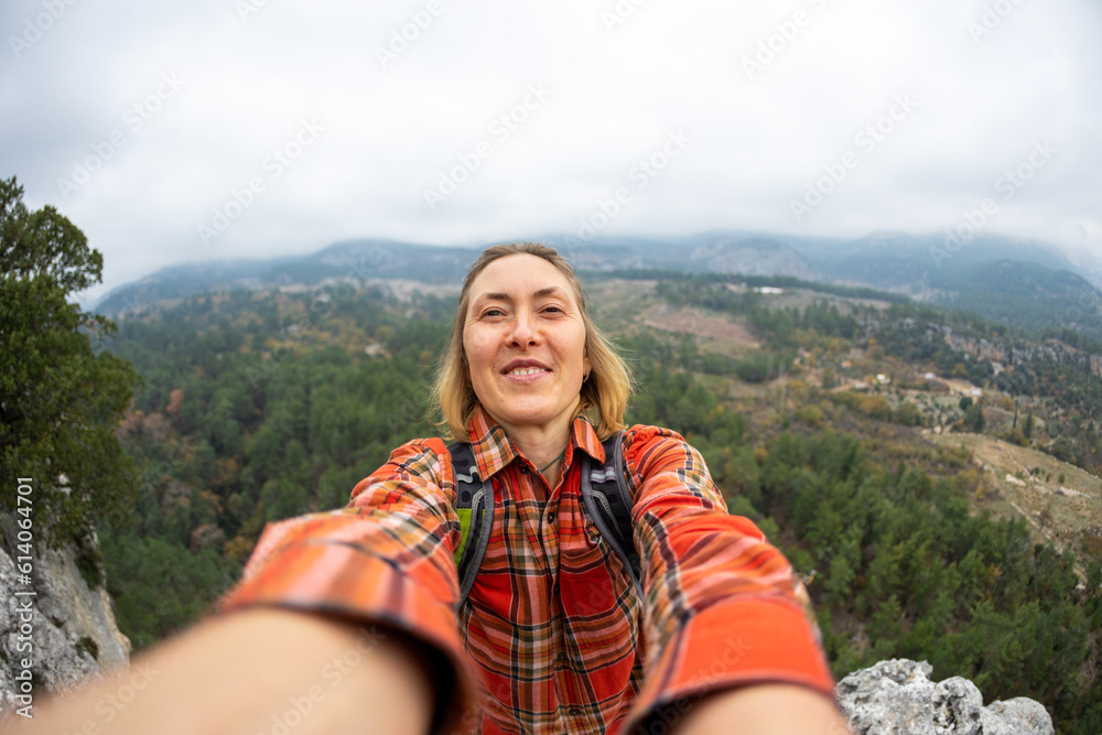 selfie of a woman on the background of a rocky and mountainous area.