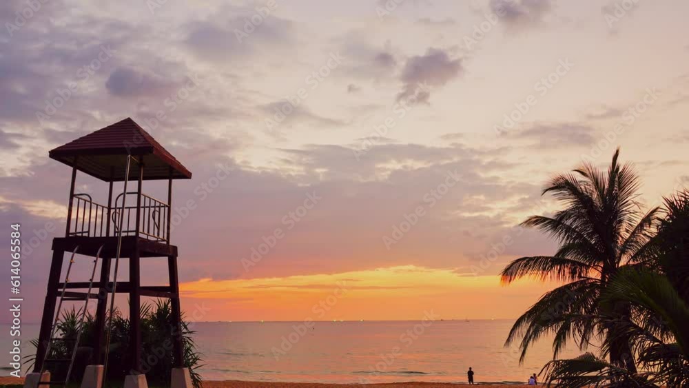 Time lapse day to night dramatic sky with colorful cloudscape.amazing sunset at Karon beach. .Gradient color colorful sky in bright sunset background. .coconut trees and lifeguard background. Time lapse day to night dramatic sky with colorful cloudscape.amazing sunset at Karon beach. .Gradient color colorful sky in bright sunset background. .coconut trees and lifeguard background.