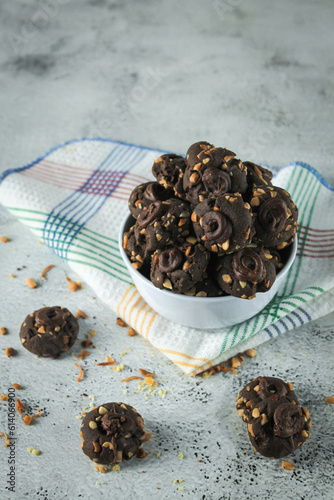 Kue coklat or Chocolate cookies or choco button cookies for Lebaran. Made from butter, egg, dark cooking chocolate, flour, cocoa pwder and cashew nut. served in grey and texture background photo