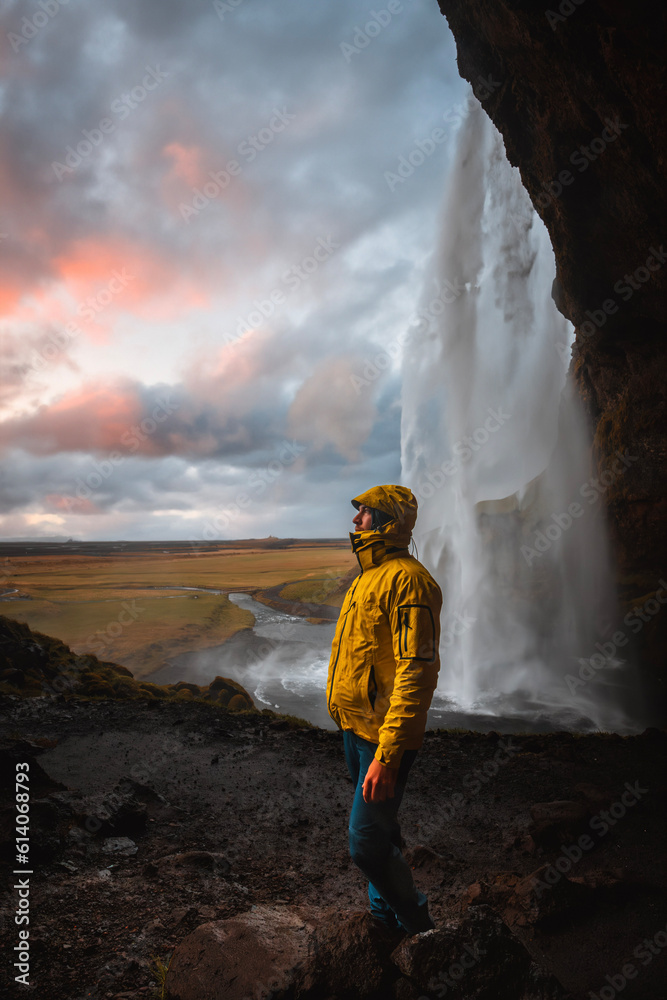 Man standing at Waterfall Seljalandsfoss in Iceland at Sunset Man standing at Waterfall Seljalandsfoss in Iceland at Sunset