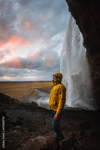 Man standing at Waterfall Seljalandsfoss in Iceland at Sunset