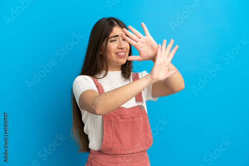 Young caucasian woman isolated on blue background nervous stretching hands to the front