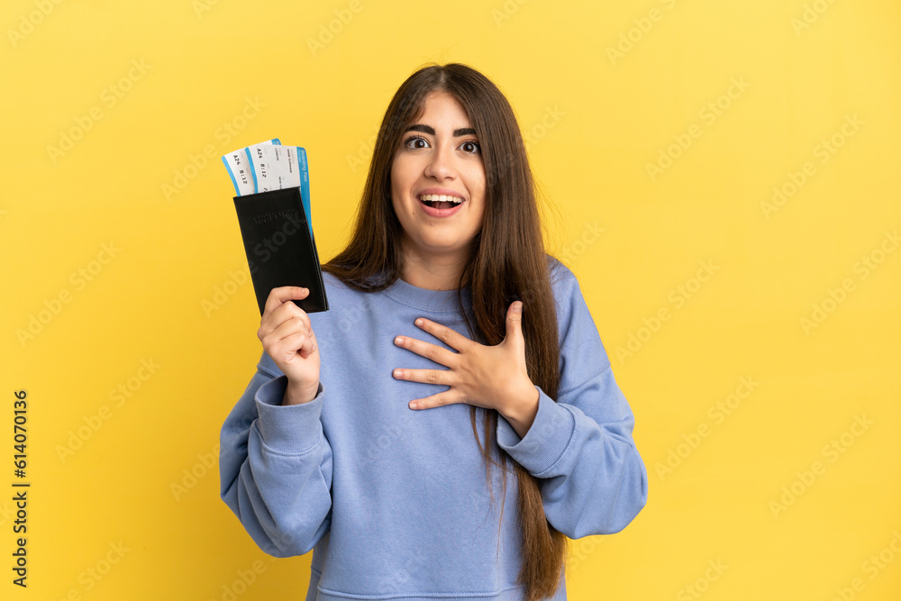 Young caucasian woman holding a passport isolated on yellow background surprised and shocked while looking right Young caucasian woman holding a passport isolated on yellow background surprised and shocked while looking right
