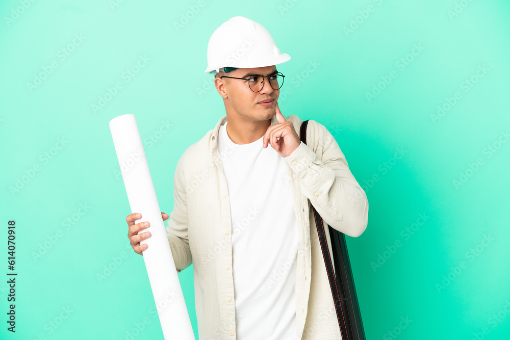 Young architect man holding blueprints over isolated background thinking an idea while looking up Young architect man holding blueprints over isolated background thinking an idea while looking up