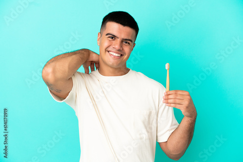 Young handsome man brushing teeth over isolated blue background laughing